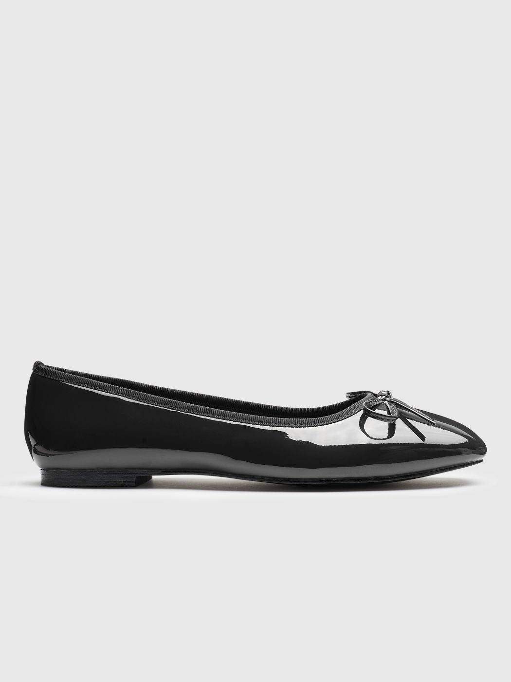 Black patent leather ballerina shoe on a light gray background