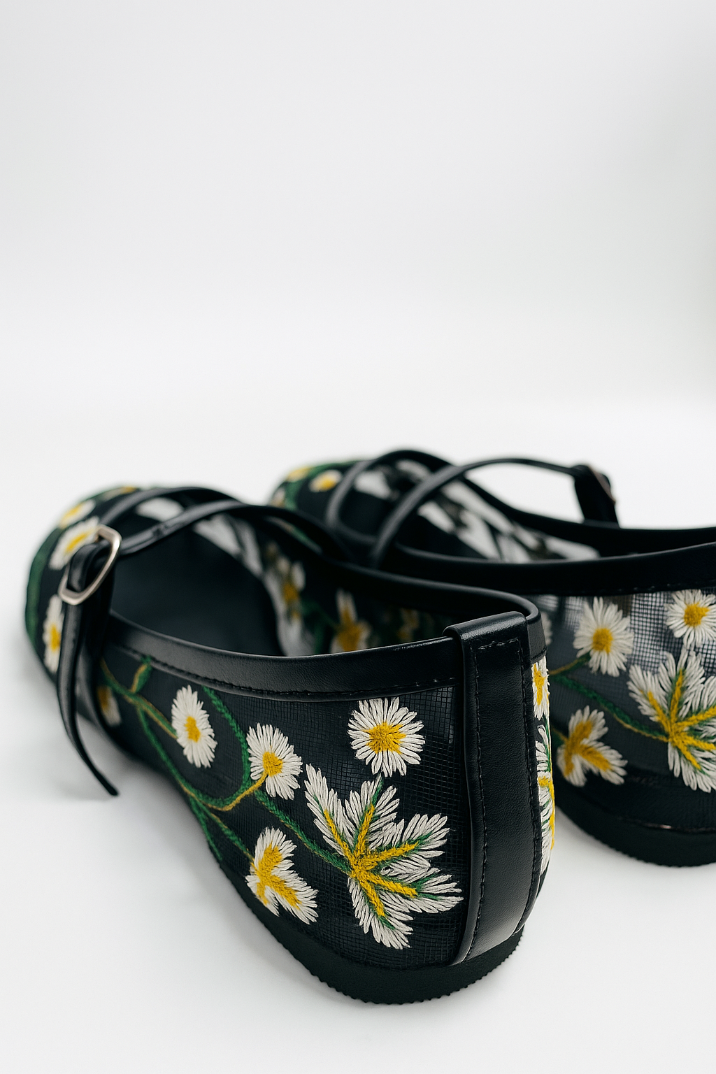 Model wearing Laal Mahal black mesh Mary Jane flats with white and yellow daisy embroidery, viewed from above on a white background