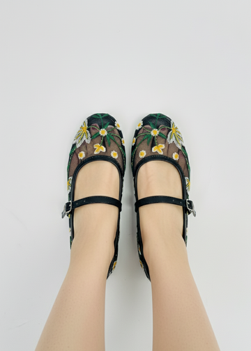 Model wearing Laal Mahal black mesh Mary Jane flats with white and yellow daisy embroidery, viewed from above on a white background