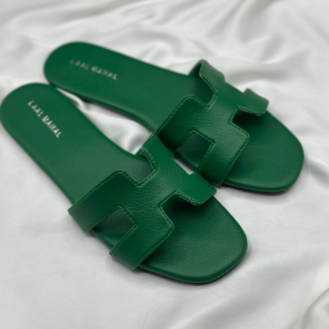 Green H-style slide flats with cutout strap, displayed on white satin background.