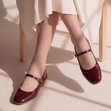 Woman wearing Bella maroon patent leather Mary Jane flats with adjustable buckle straps and a glossy finish, styled for everyday comfort and elegant casual wear.