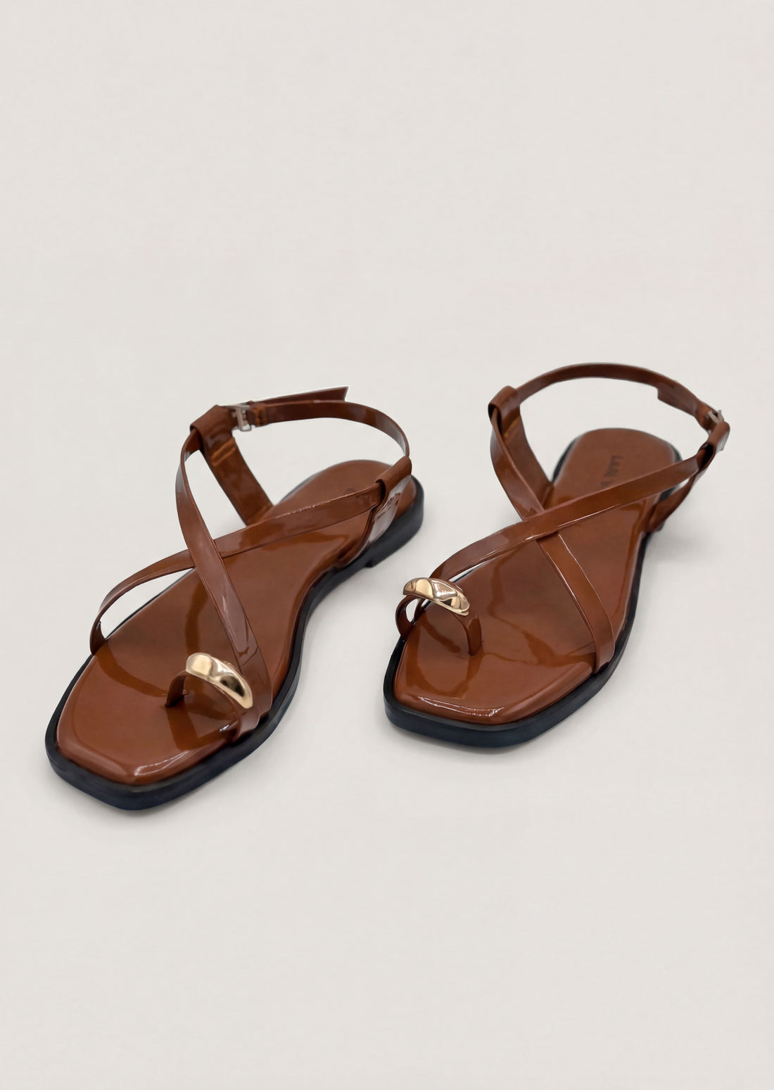 Cocoa Vibe brown patent cross strap flat sandals on feet women Pakistan – Laal Mahal