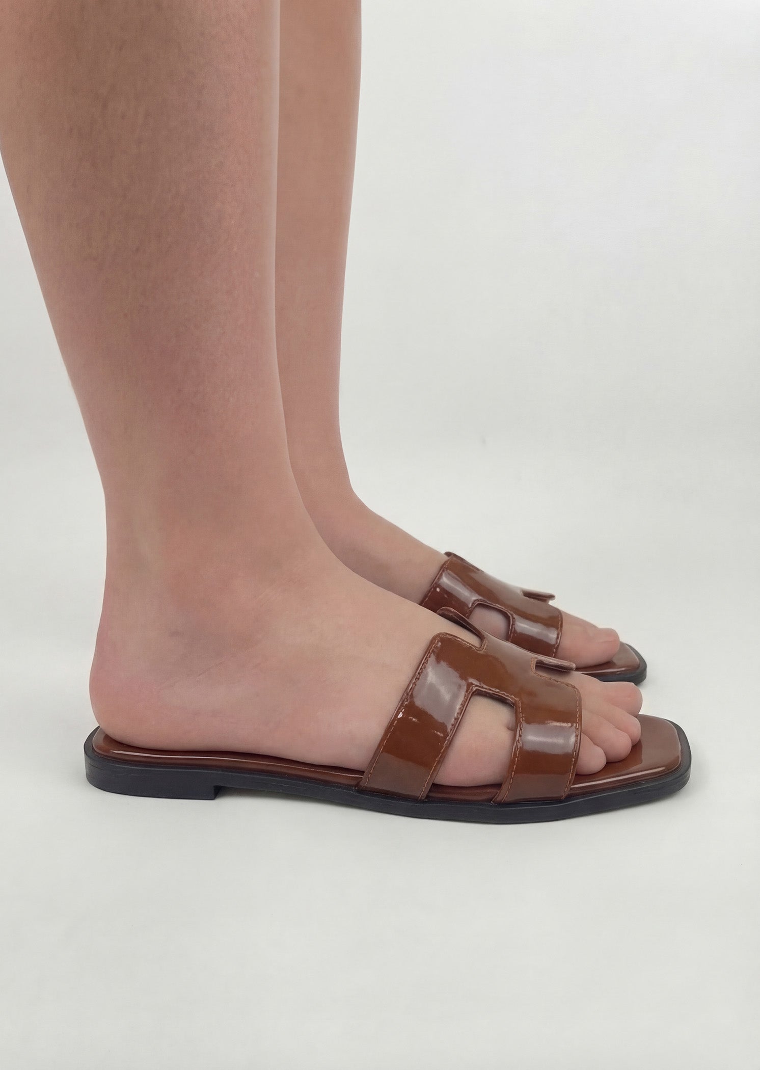 Hazel Hue brown patent H-strap slide flat sandals on feet side view women Pakistan – Laal Mahal