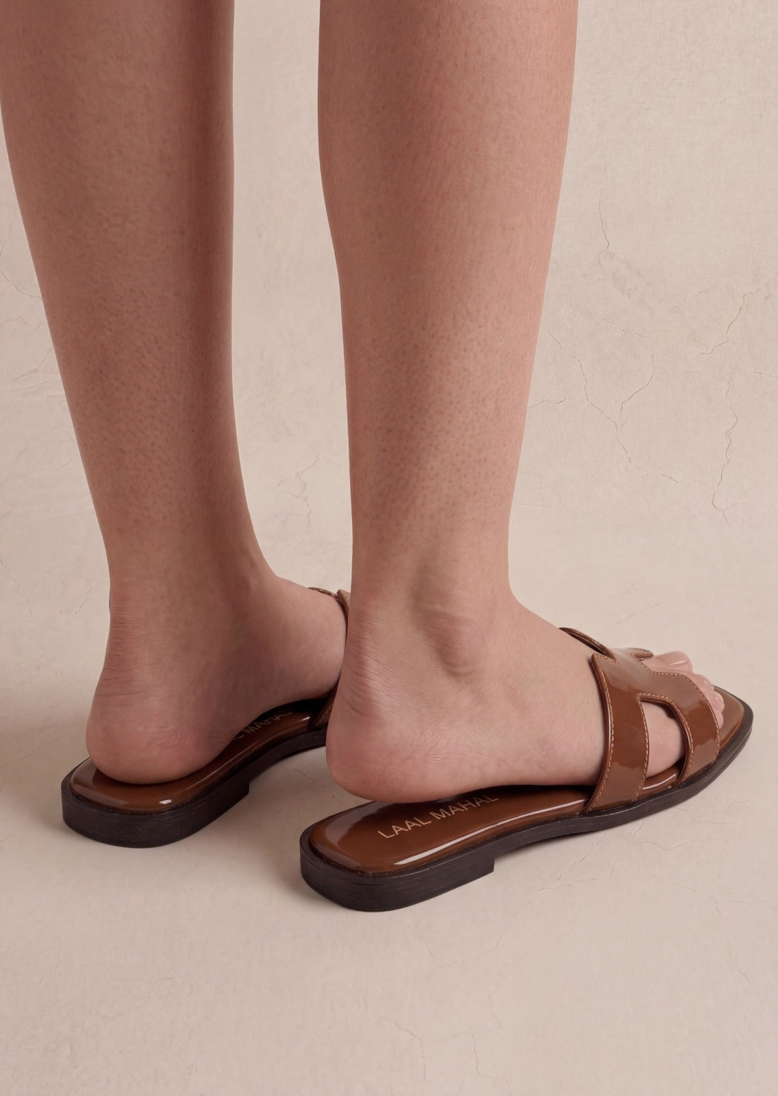 Woman wearing Hazel Hue brown patent slide flats standing – Laal Mahal Pakistan