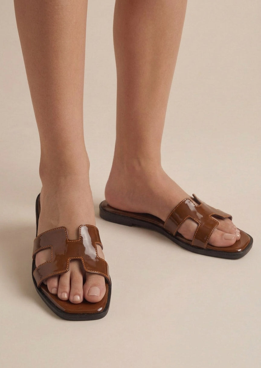 Hazel Hue tan patent H-strap slide flat sandals on feet women Pakistan – Laal Mahal