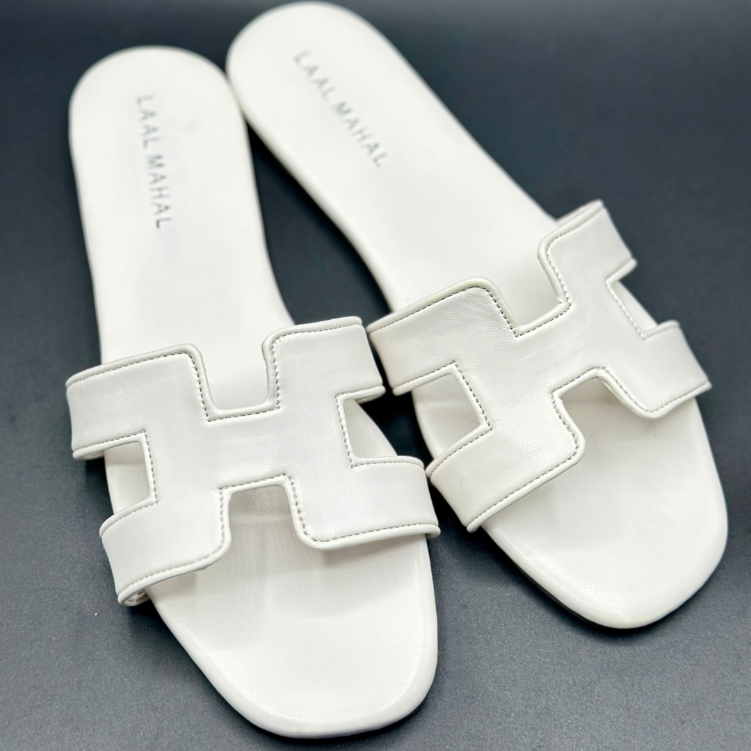 Women’s white H-style flat sandals with cut-out straps, non-slip sole, and detailed stitching, product flat-lay on dark background.