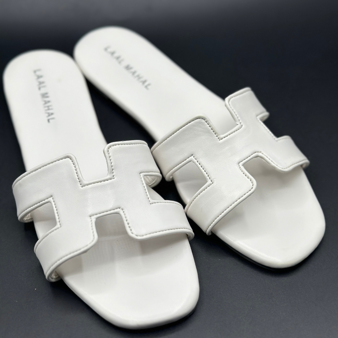 Women’s white H-style flat sandals with cut-out straps, non-slip sole, and detailed stitching, product flat-lay on dark background.