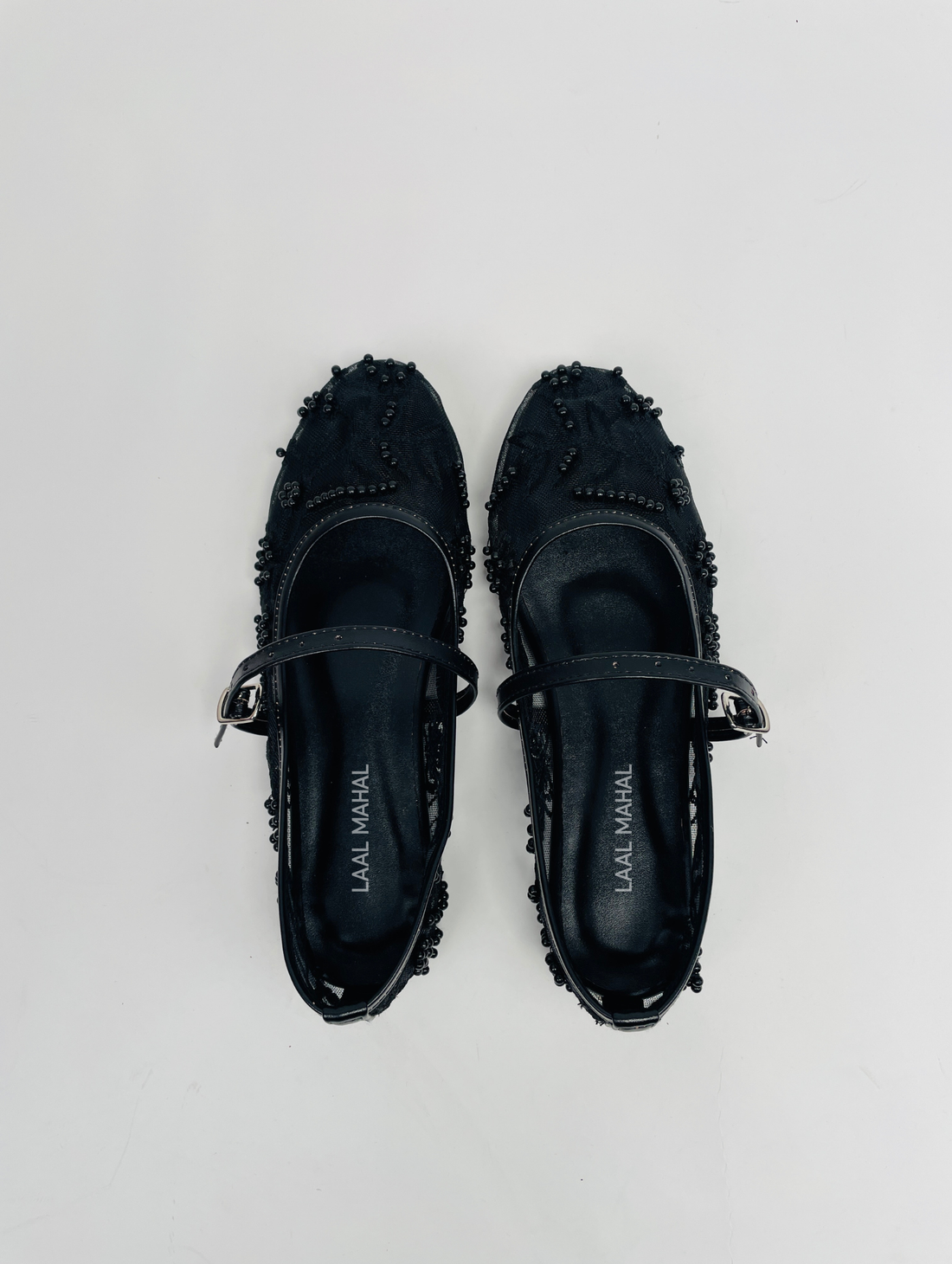 Pair of black loafers with fringe details on a light gray background