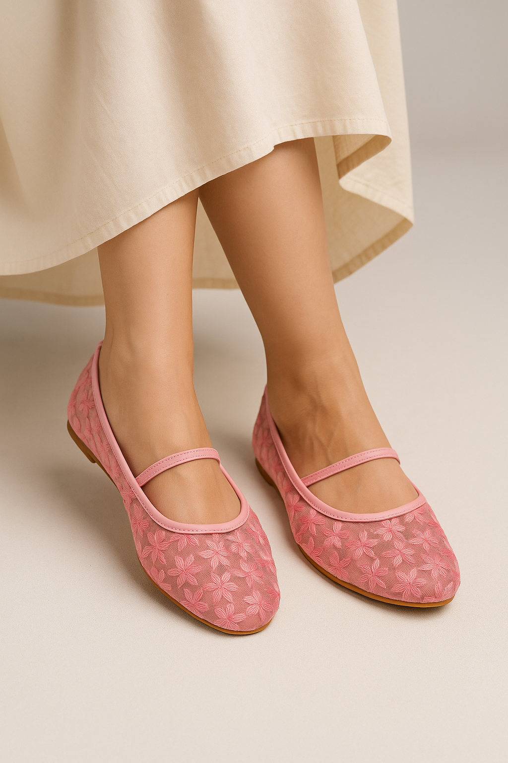 Pink floral-patterned flats worn with a beige skirt on a neutral background