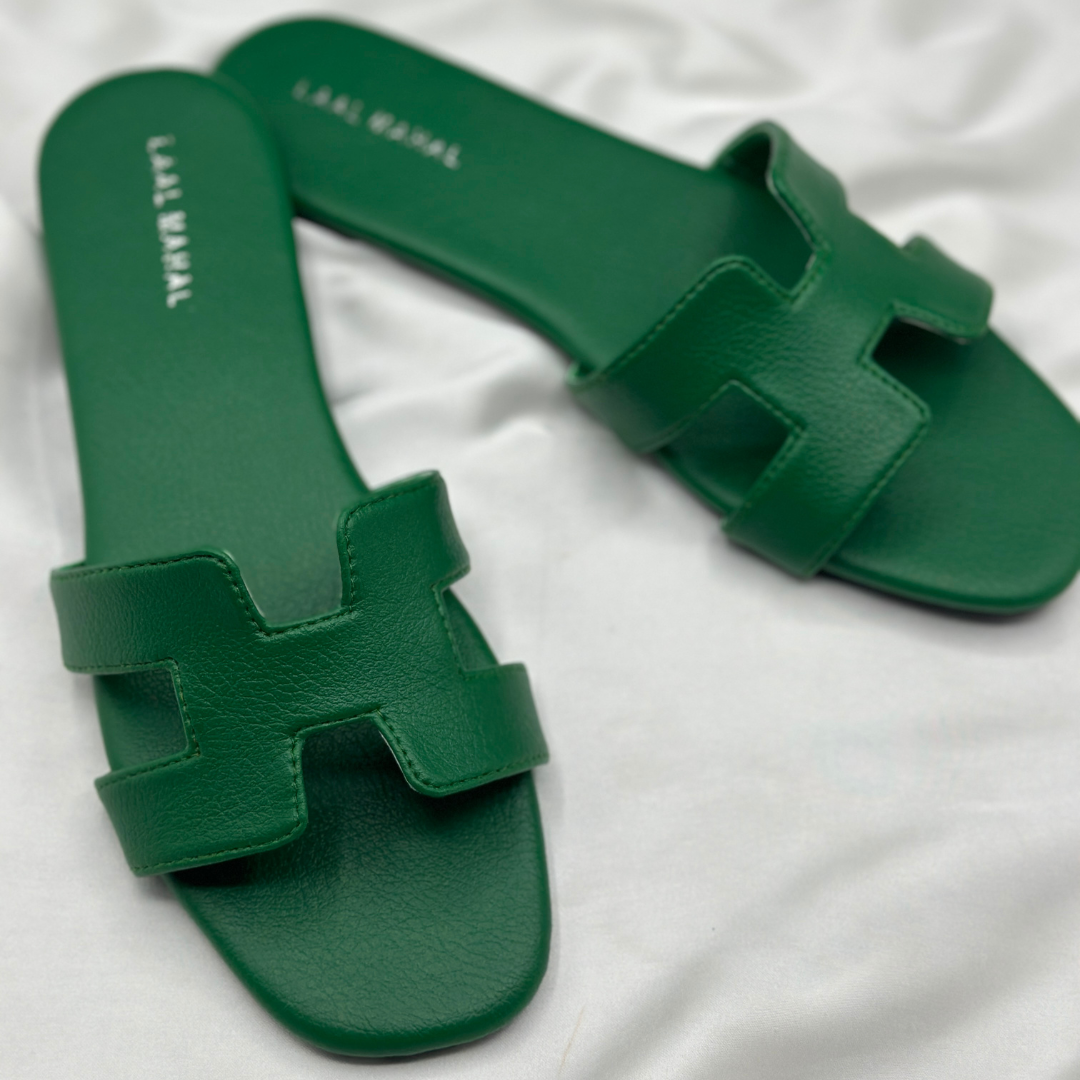 Green H-style slide flats with cutout strap, displayed on white satin background.