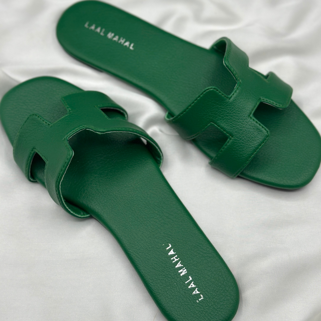 Green H-style slide flats with cutout strap, displayed on white satin background.
