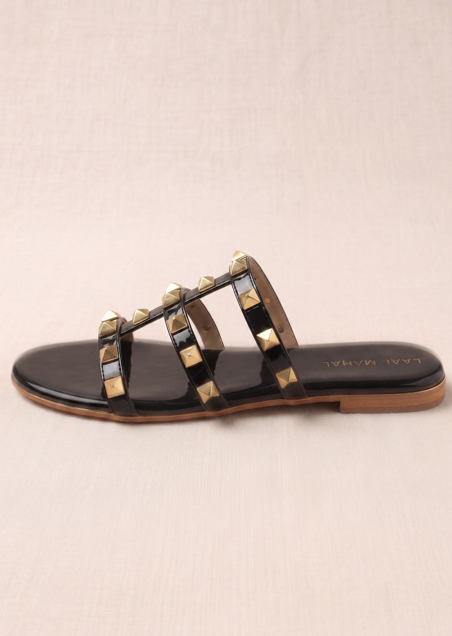 Laal Mahal Rockstud Flat Slide Sandals black patent side view with gold stud triple straps and gold-trimmed sole