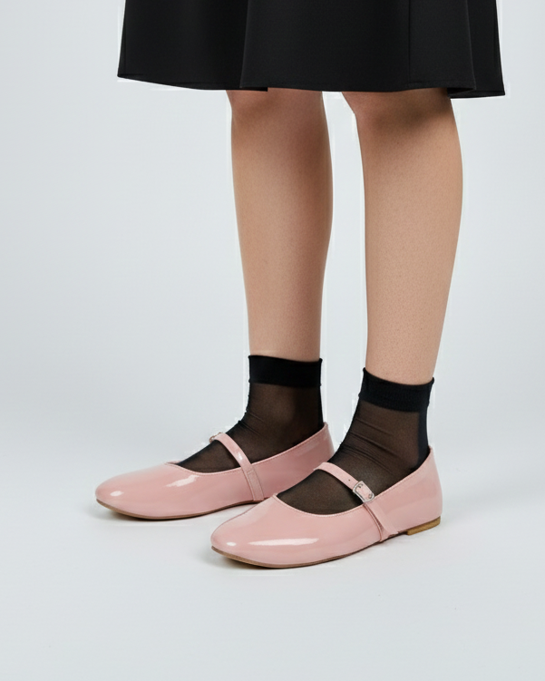 Person wearing black shoes with soft pink mary janes flats and sheer black socks on a white background
